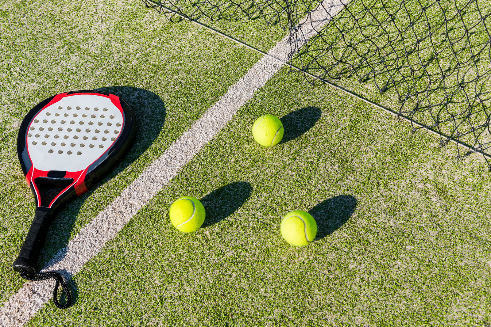 Green padel field with racket and tennis balls