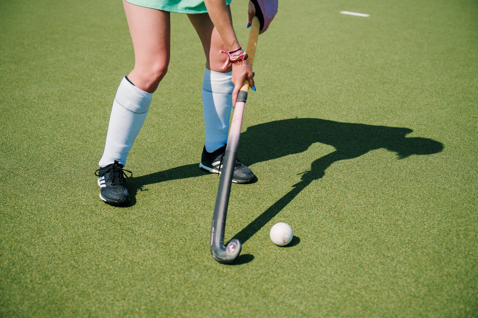 Hockey field with player and her shadow - Ball on green turf field - Act Sports, the Premium Artificial Sports Turf Supplier