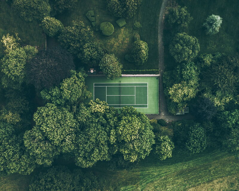 Tennis court in woods - Ball on green turf field - Act Sports, the Premium Artificial Sports Turf Supplier