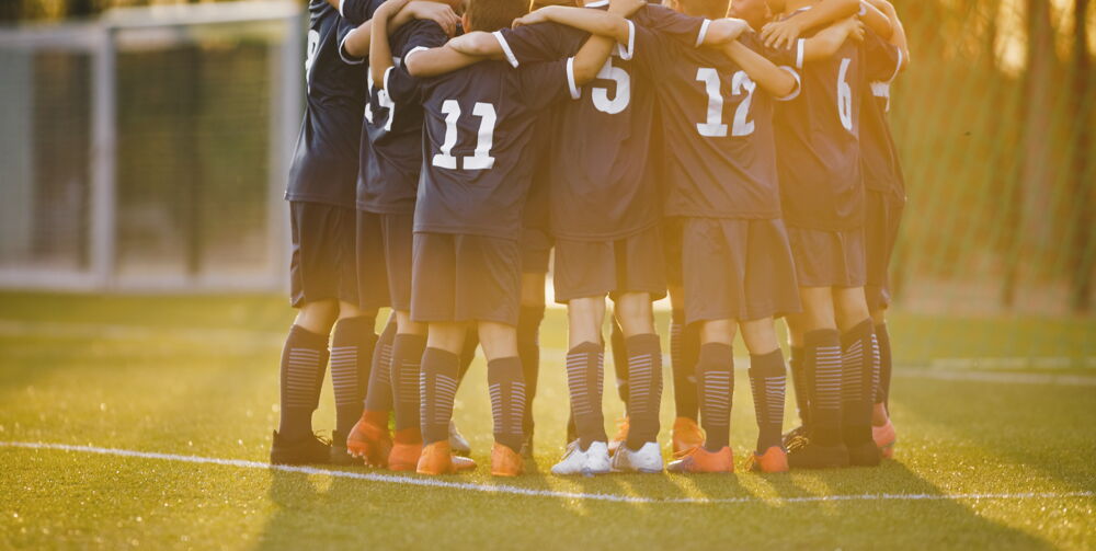 group huddle - Ball on green turf field - Act Sports, the Premium Artificial Sports Turf Supplier